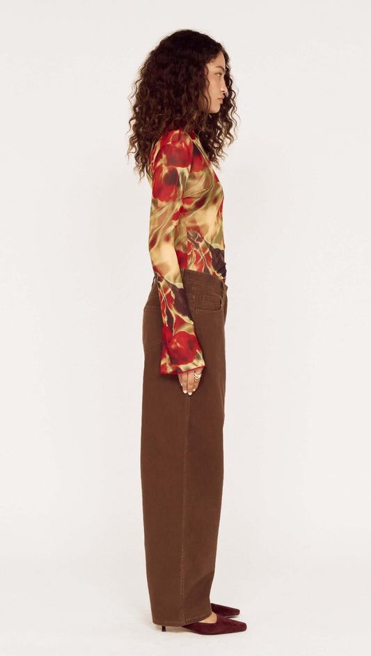 Model showcasing Brown Mid Rise Barrel Leg Jeans from the side, paired with a colorful floral top.