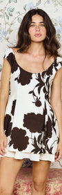 Model wearing the Brown and Cream Floral Layered Mini Dress against a floral wallpaper background.
