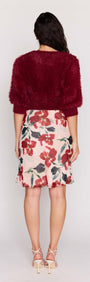 A model wearing a Burgundy Cropped Fluffy Knit Sweater paired with a floral skirt from the back.