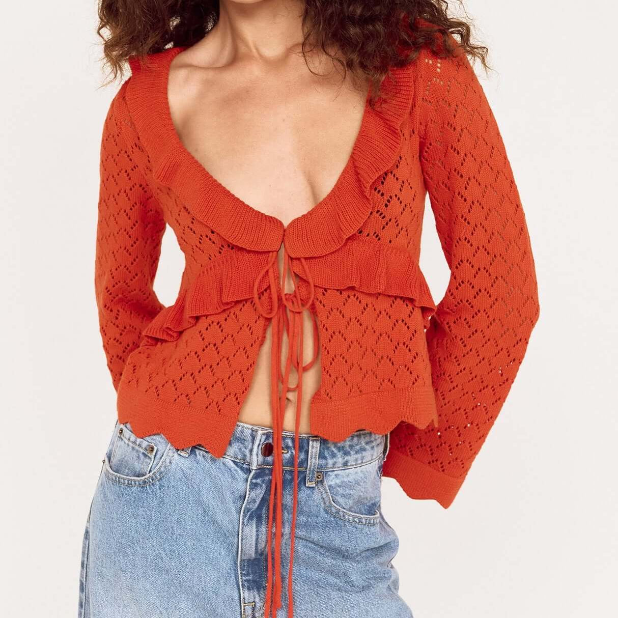 Model wearing a Burnt Orange Pointelle Tie Front Top with casual denim jeans, featuring a playful and feminine knit design.