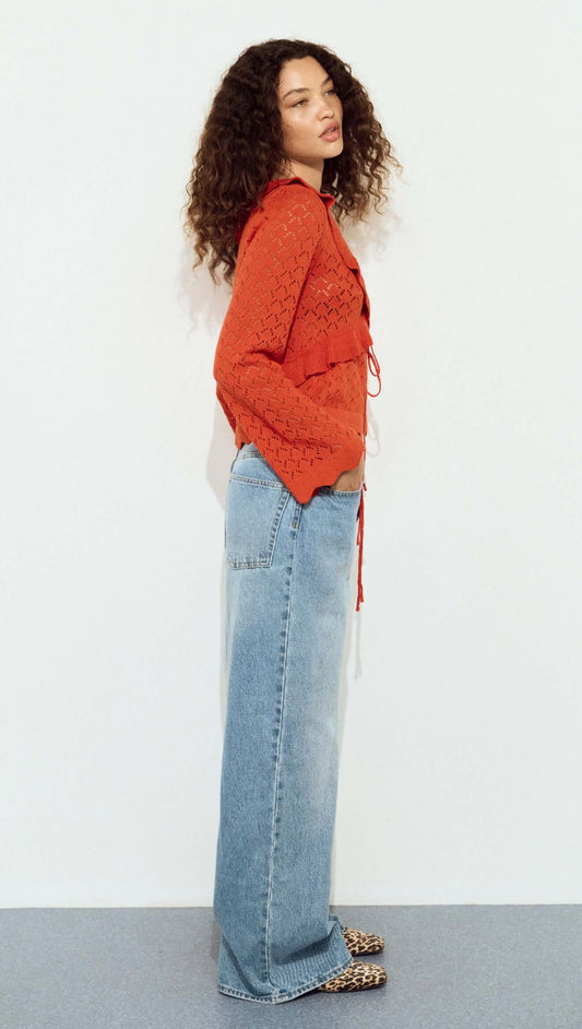 Model wearing a Burnt Orange Pointelle Tie Front Top with blue wide-leg jeans and animal print shoes.