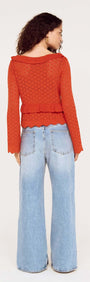 Model wearing a Burnt Orange Pointelle Tie Front Top with flared jeans, showcasing a stylish back view.