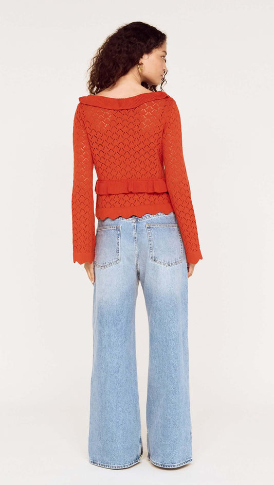 Model wearing a Burnt Orange Pointelle Tie Front Top with flared jeans, showcasing a stylish back view.