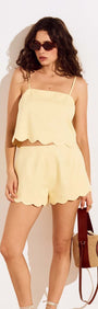 Model wearing Butter Yellow Cotton Blend Scallop Hem Shorts with a matching scallop hem top and sunglasses.