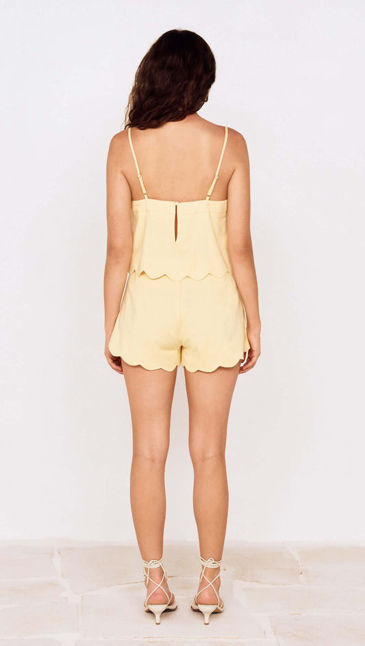 Back view of a model wearing Butter Yellow Cotton Blend Scallop Hem Shorts paired with a matching top.