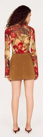 Back view of model wearing a Button Front Faux Sude Mini Skirt styled with a floral long-sleeve top.