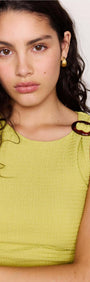 Model wearing a Chartreuse Ruched Mini Dress featuring subtle shoulder ring detail and textured fabric.