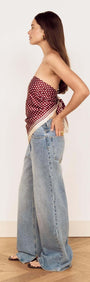 Model showcasing the Chocolate Polka Dot Scarf styled as a bandeau top with high-waisted denim jeans.