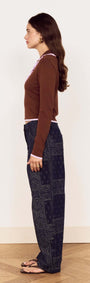 Model showcasing the Chocolate Ruffle Collar Polo Knit Top with relaxed denim, giving a chic profile view.