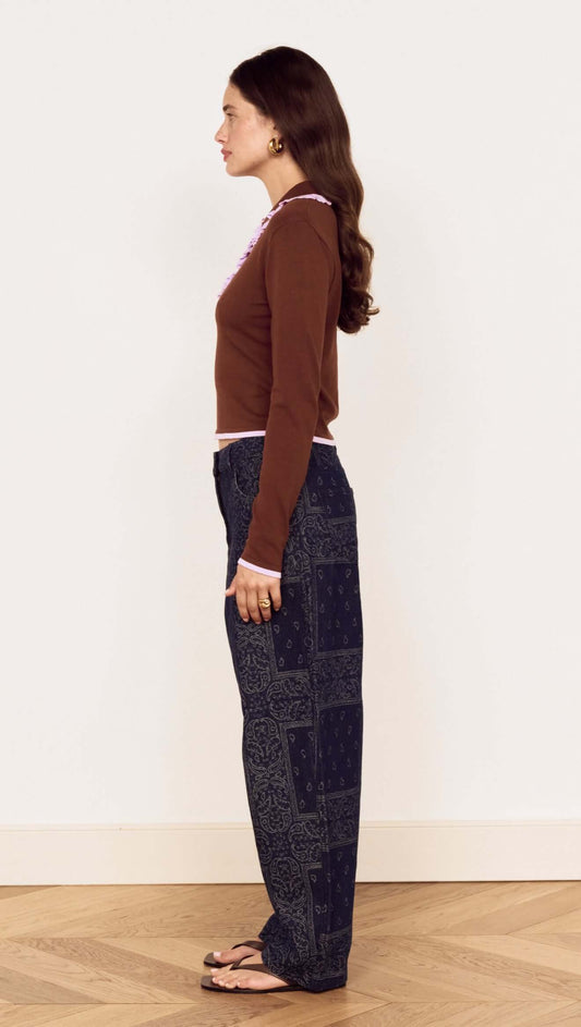 Model showcasing the Chocolate Ruffle Collar Polo Knit Top with relaxed denim, giving a chic profile view.