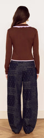 Back view of a model wearing a Chocolate Ruffle Collar Polo Knit Top paired with stylish patterned wide-leg pants.
