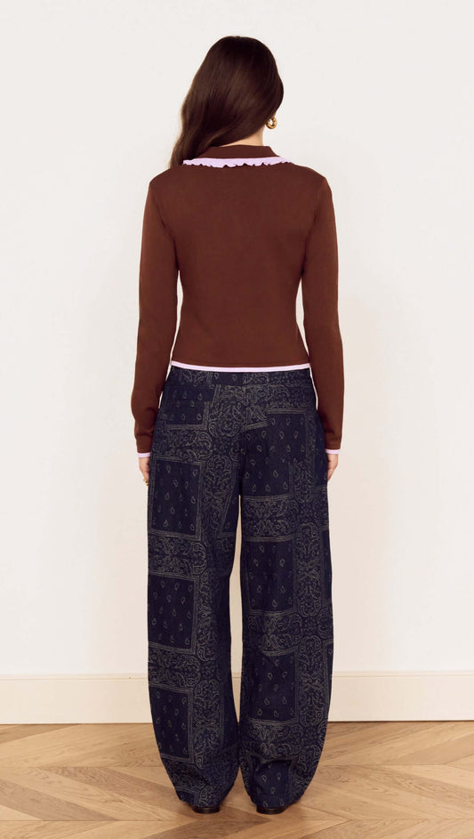 Back view of a model wearing a Chocolate Ruffle Collar Polo Knit Top paired with stylish patterned wide-leg pants.