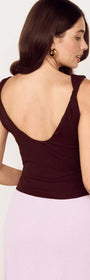 Woman wearing the Chocolate Twist Shoulder Mesh Top with a low scoop back and twist shoulder details.