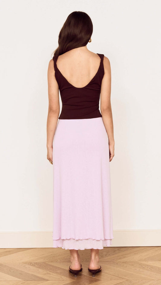 Back view of a model wearing the stylish Chocolate Twist Shoulder Mesh Top and a pastel pink skirt.