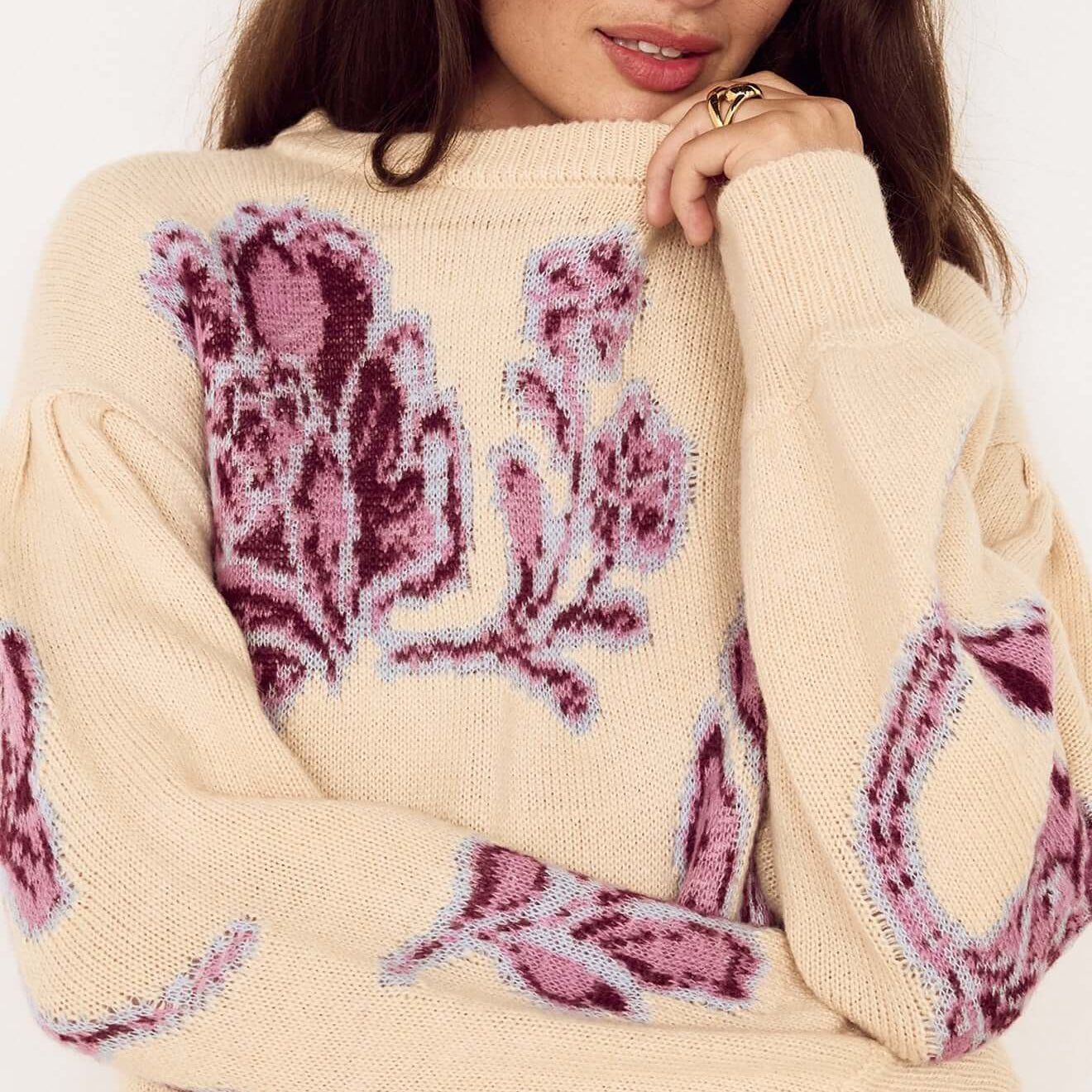 Model wearing a Cream Floral Intarsia Knit Sweater with floral motifs in wine and lilac, smiling at the camera.