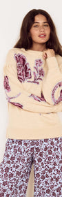 Woman wearing a Cream Floral Intarsia Knit Sweater featuring floral motifs in wine and lilac, styled with printed trousers.