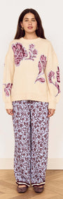 A model wearing the Cream Floral Intarsia Knit Sweater with floral design, paired with printed pants.