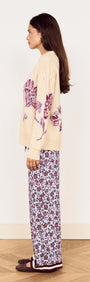 Model wearing a Cream Floral Intarsia Knit Sweater with floral design, styled with printed pants.