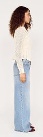 Model wearing a Cream Pointelle Knit Cardi with Tie Front, showing side view, paired with loose-fitting jeans.