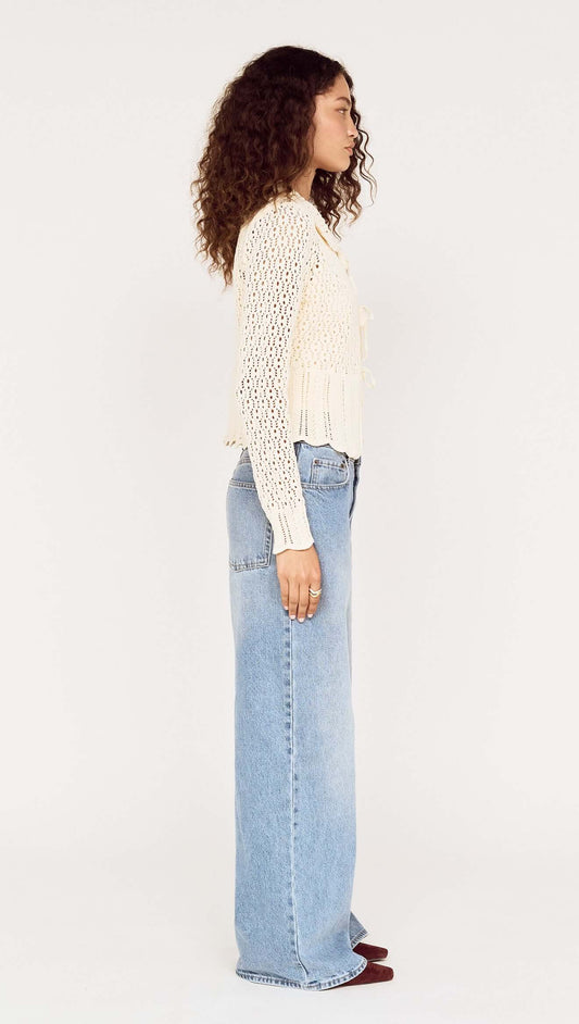 Model wearing a Cream Pointelle Knit Cardi with Tie Front, showing side view, paired with loose-fitting jeans.