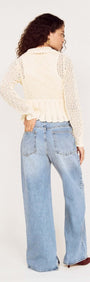 Woman wearing a Cream Pointelle Knit Cardi with Tie Front over baggy jeans, showing the back view with a soft, feminine design.