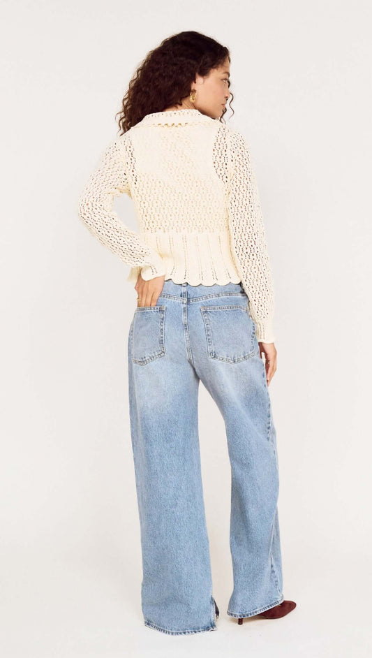 Woman wearing a Cream Pointelle Knit Cardi with Tie Front over baggy jeans, showing the back view with a soft, feminine design.