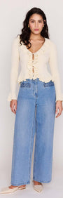 Model wearing a Cream Ruffled Cardigan with ruffle trim, paired with wide-leg jeans.