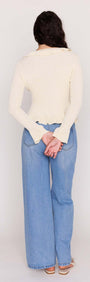 Back view of a model wearing a Cream Ruffled Cardigan with fluted hems and casual blue jeans.