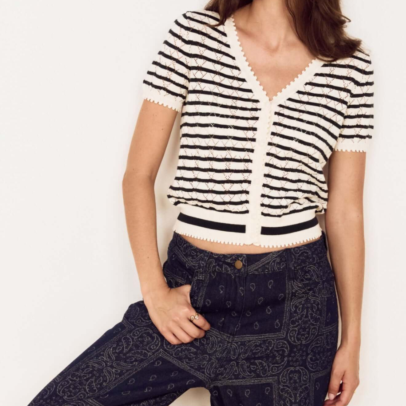 Model wearing Cream Stripe Cotton Pointelle Knit Top with denim pants, showcasing a stylish layered look.