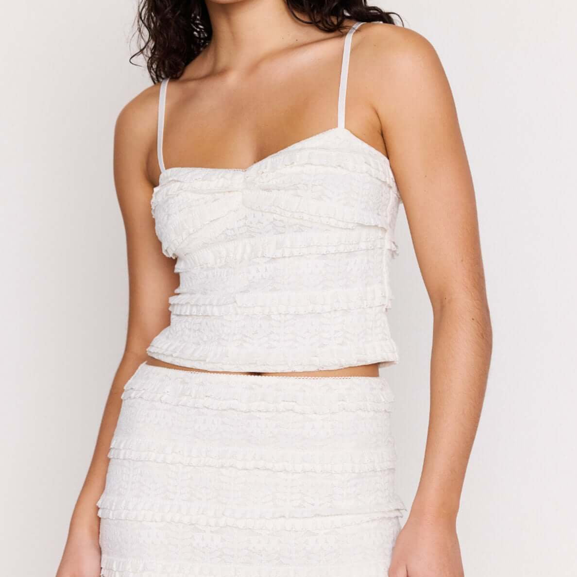 Model wearing the Cream Textured Lace Cropped Cami Top featuring slim straps and tiered lace detailing.