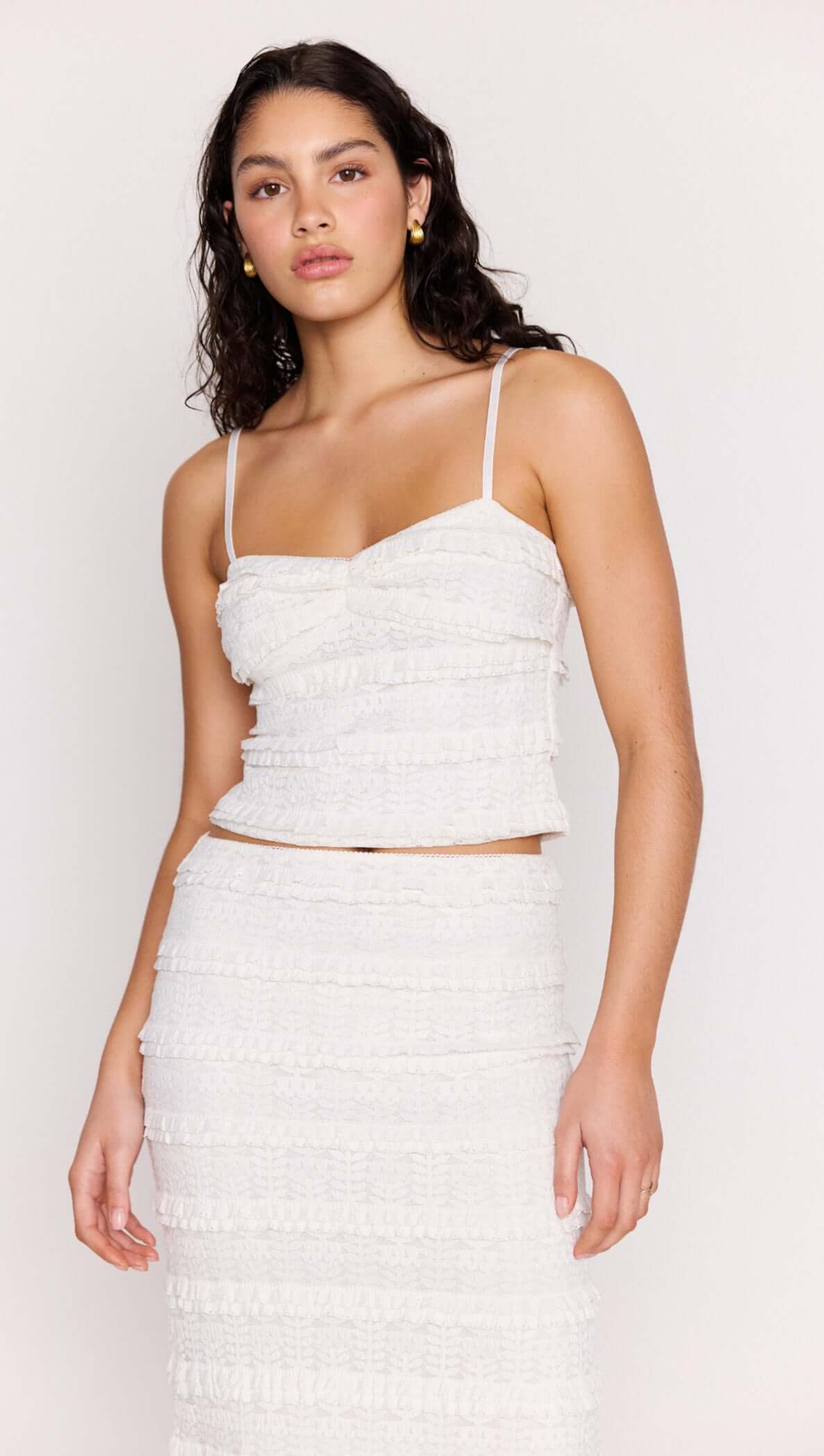 Model wearing the Cream Textured Lace Cropped Cami Top featuring slim straps and tiered lace detailing.
