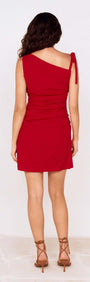 Back view of a woman wearing a Deep Red Tie Shoulder Mini Dress, showcasing its ruched design and tie shoulder detail.