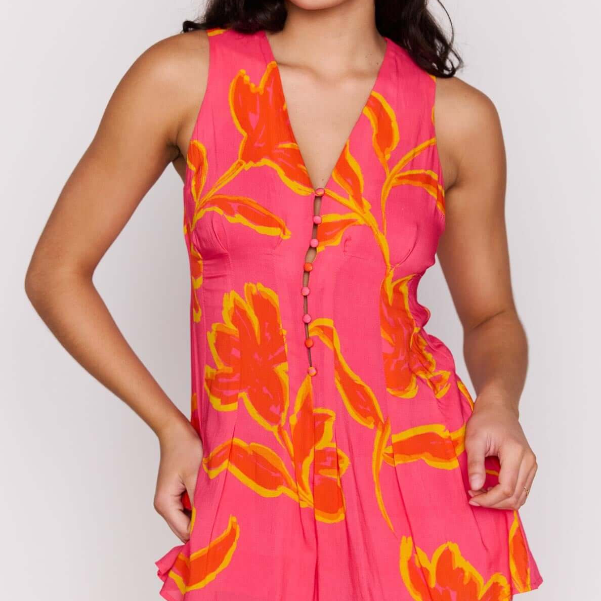 Model showcasing the ELODIE SLEEVELESS PLAYSUIT in vibrant pink with floral patterns.