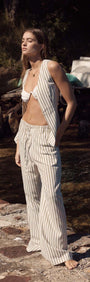 Model showcasing Olive & White Stripe Cotton Blend Relaxed Pant by the water, highlighting its breezy style.
