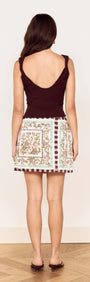 Back view of a model wearing the Floral Scarf Print Wrap Mini Skirt with a chic top and stylish shoes.
