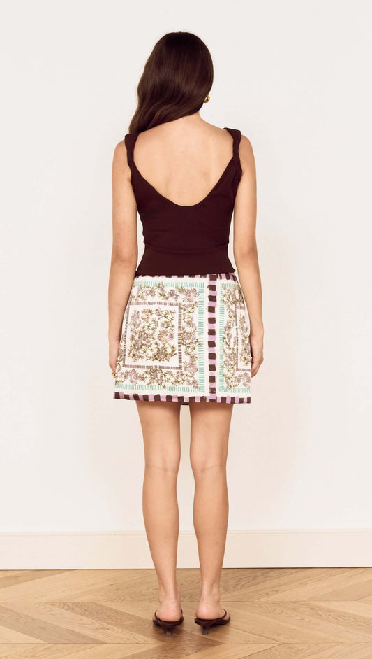 Back view of a model wearing the Floral Scarf Print Wrap Mini Skirt with a chic top and stylish shoes.