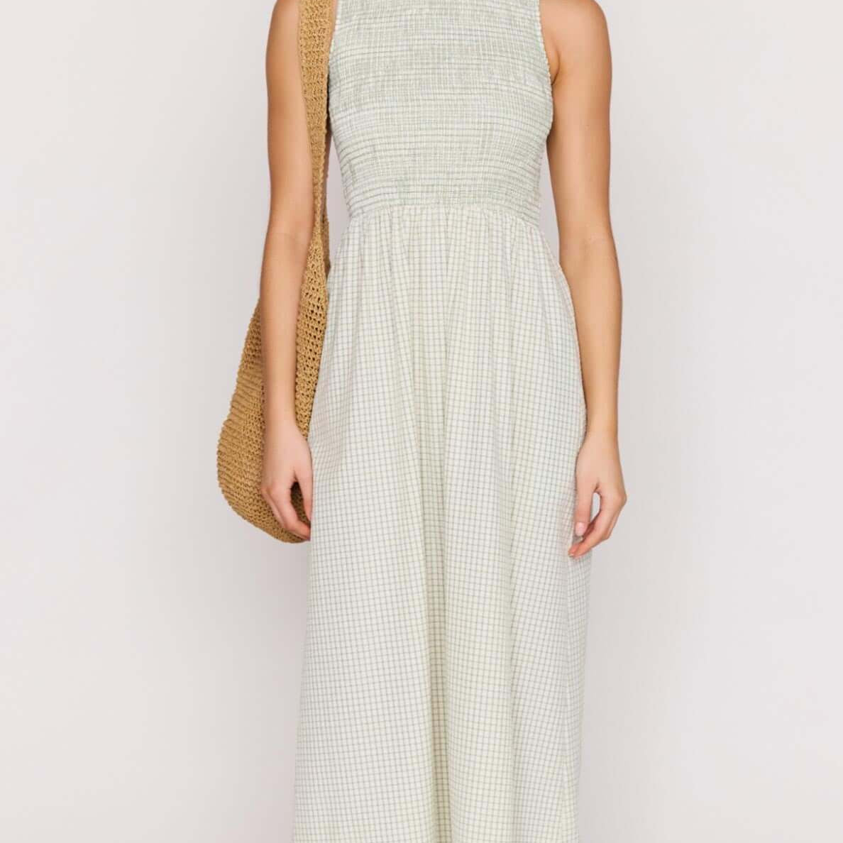 Model wearing the Green Gingham Smocked Midi Dress with a stylish bag, showcasing a fresh summer look.