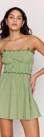Playful model wearing the Green Striped Linen Blend Scallop Mini Dress with a flared mini skirt and scalloped edges.