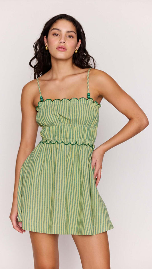 Playful model wearing the Green Striped Linen Blend Scallop Mini Dress with a flared mini skirt and scalloped edges.
