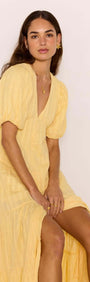 A model wearing a Relaxed Yellow Cotton Tiered Maxi Dress, showcasing its flowy design and V-neckline.