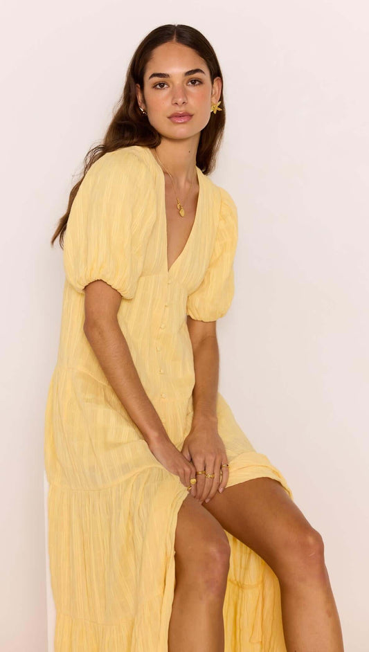 A model wearing a Relaxed Yellow Cotton Tiered Maxi Dress, showcasing its flowy design and V-neckline.