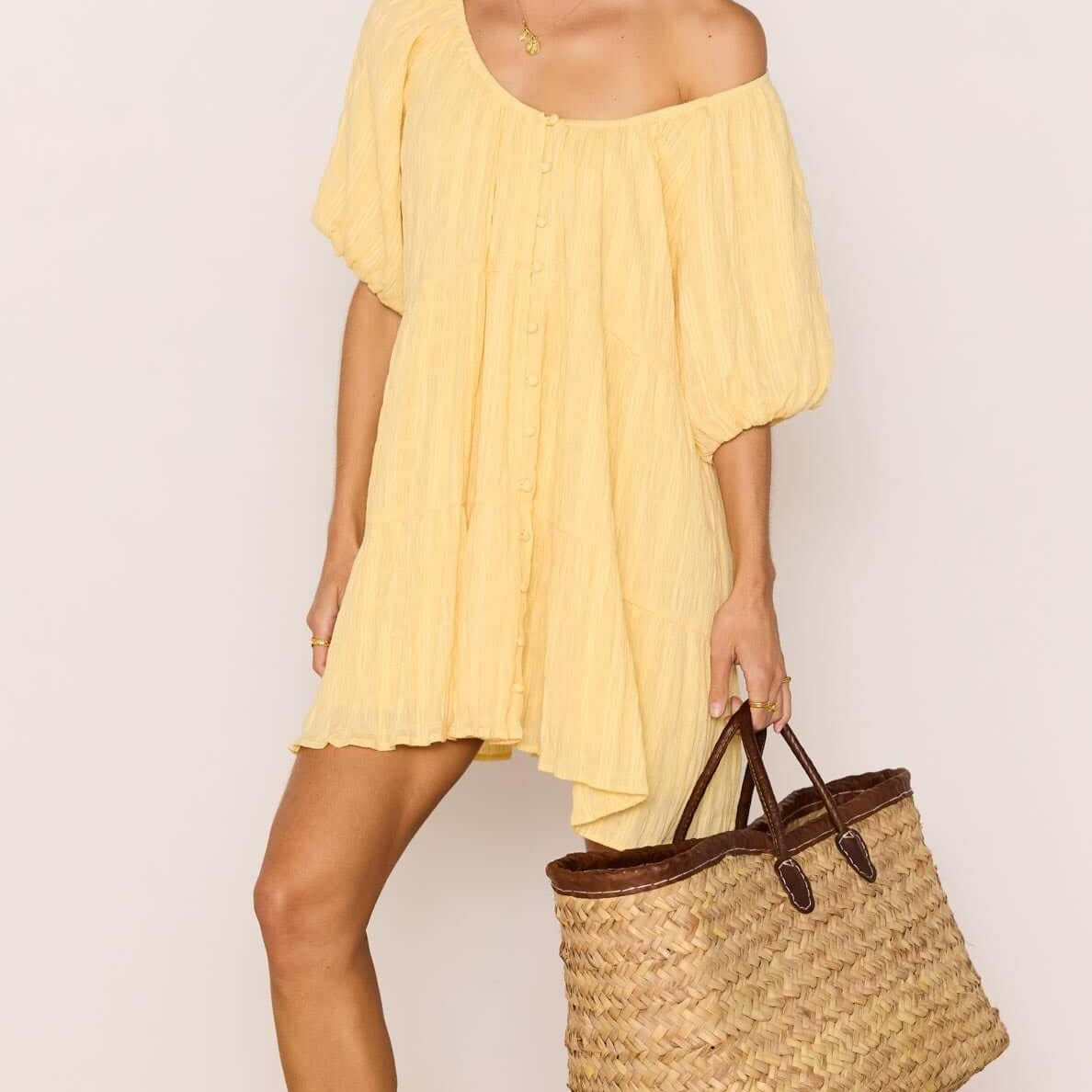 Relaxed Yellow Cotton Tiered Mini Dress worn with a woven bag, perfect for summer outings.