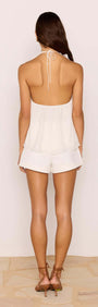 Back view of a woman wearing a White Ruffle Halter Top paired with shorts, showcasing a stylish and feminine look.