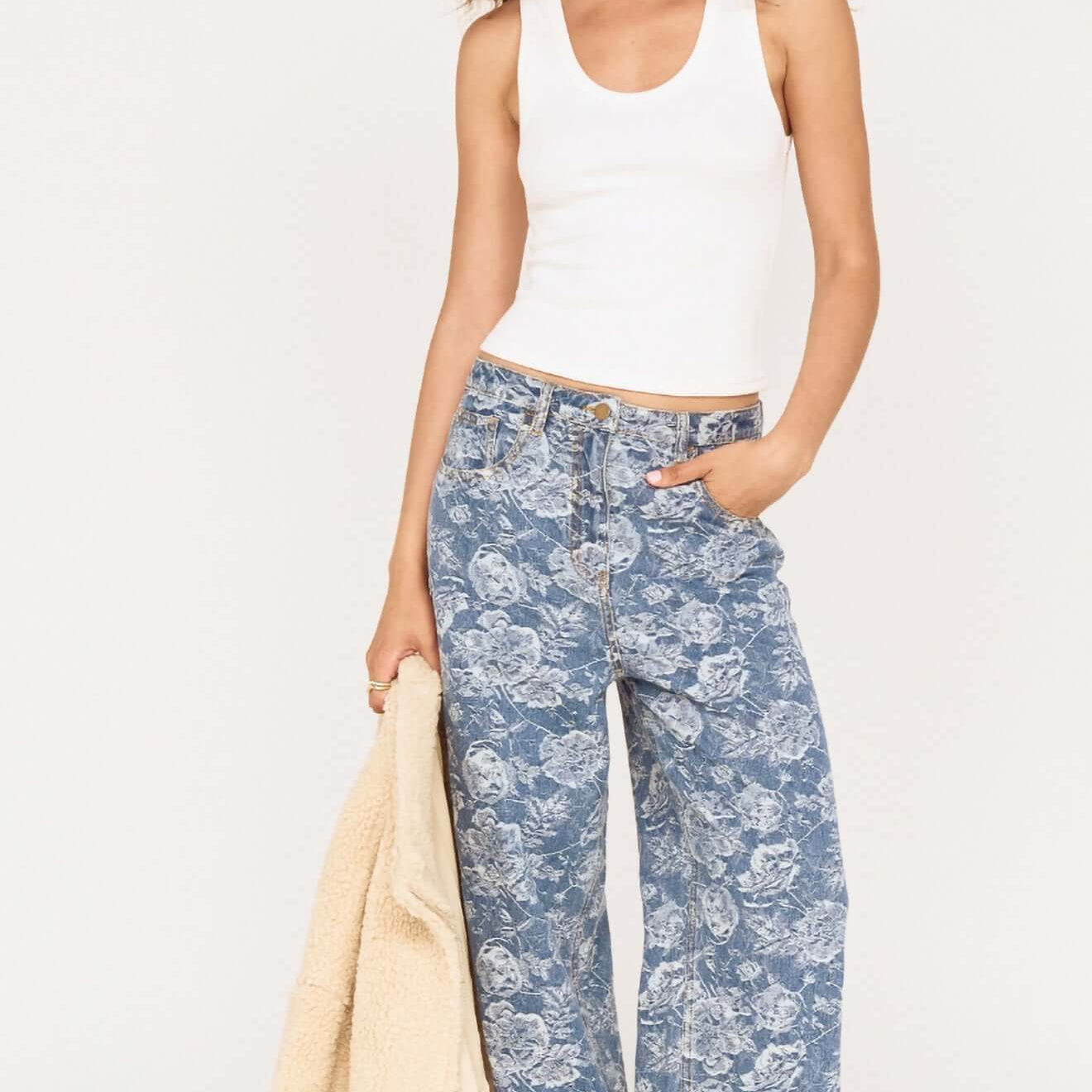 Woman wearing Mid Rise Floral Denim Wide Leg Jeans with a white tank top and beige jacket.