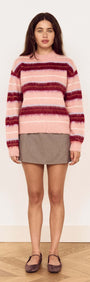 Model wearing a Pink Brushed Stripe Crew Neck Sweater over a skirt, showcasing its soft texture and vibrant colors.