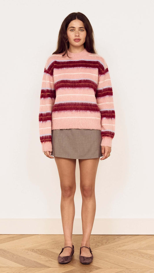 Model wearing a Pink Brushed Stripe Crew Neck Sweater over a skirt, showcasing its soft texture and vibrant colors.