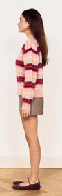 Young woman wearing a Pink Brushed Stripe Crew Neck Sweater with a relaxed fit and side view, styled over a mini skirt.