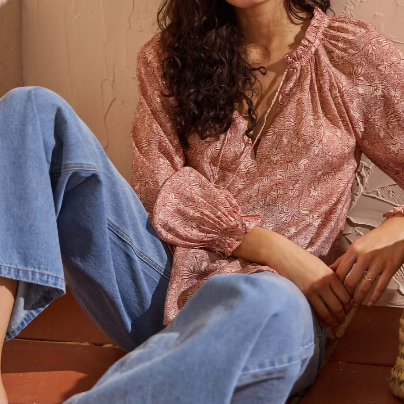 Model wearing a Red Floral Peasant Blouse, styled with relaxed denim jeans, showcasing elegant boho fashion.