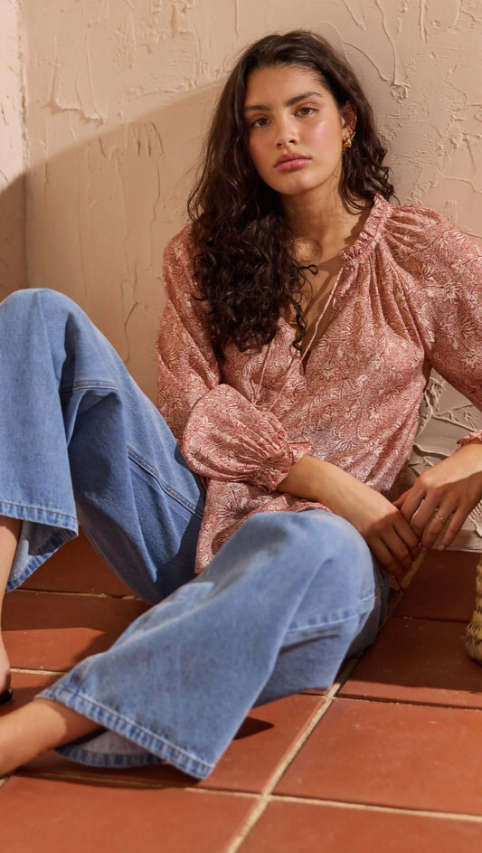 Model wearing a Red Floral Peasant Blouse, styled with relaxed denim jeans, showcasing elegant boho fashion.