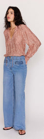 Model wearing a Red Floral Peasant Blouse with billowed sleeves and V neckline, paired with wide-leg jeans.